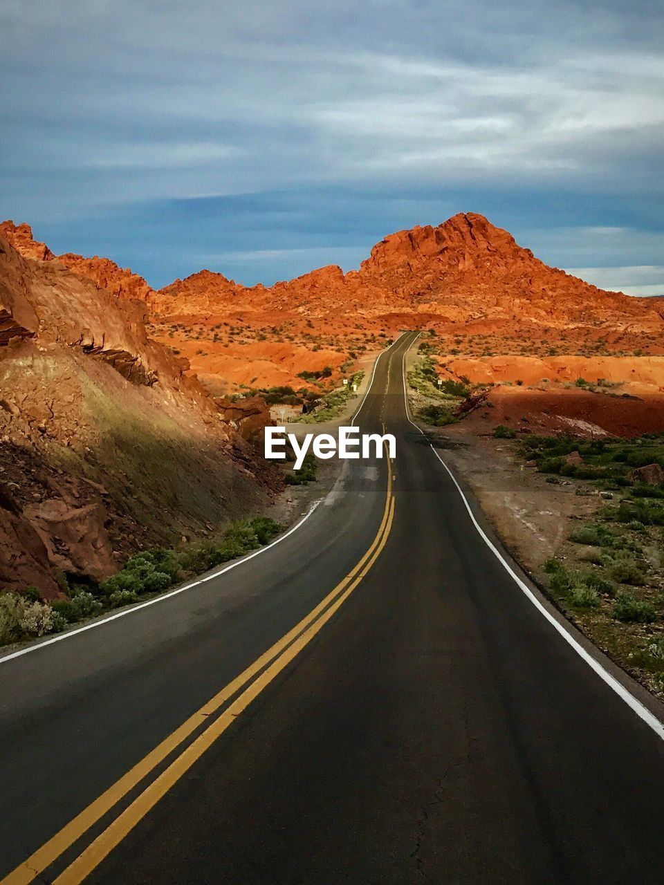 Road leading towards mountains against sky