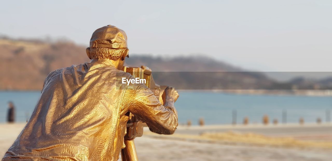 temple, statue, monument, sculpture, religion, gold, focus on foreground, water, belief, representation, ancient history, travel destinations, spirituality, nature, sky, architecture, sand, human representation, day, craft, travel, outdoors, history, no people, beauty in nature, city, the past