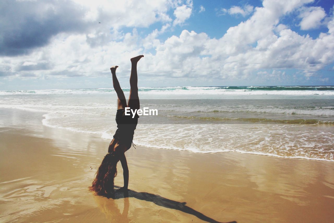 Woman doing handstand on beach