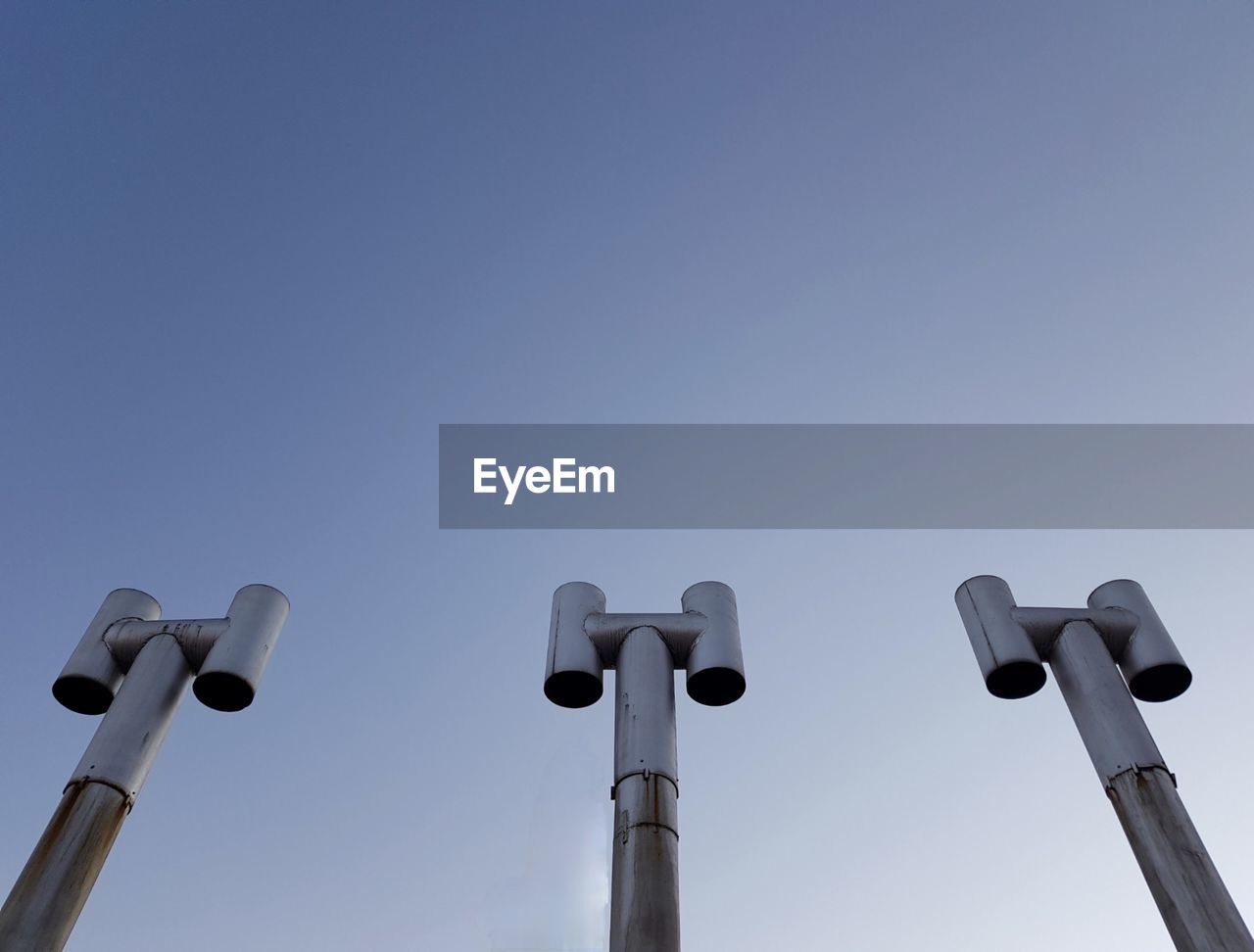 Low angle view of electric lamp against clear blue sky