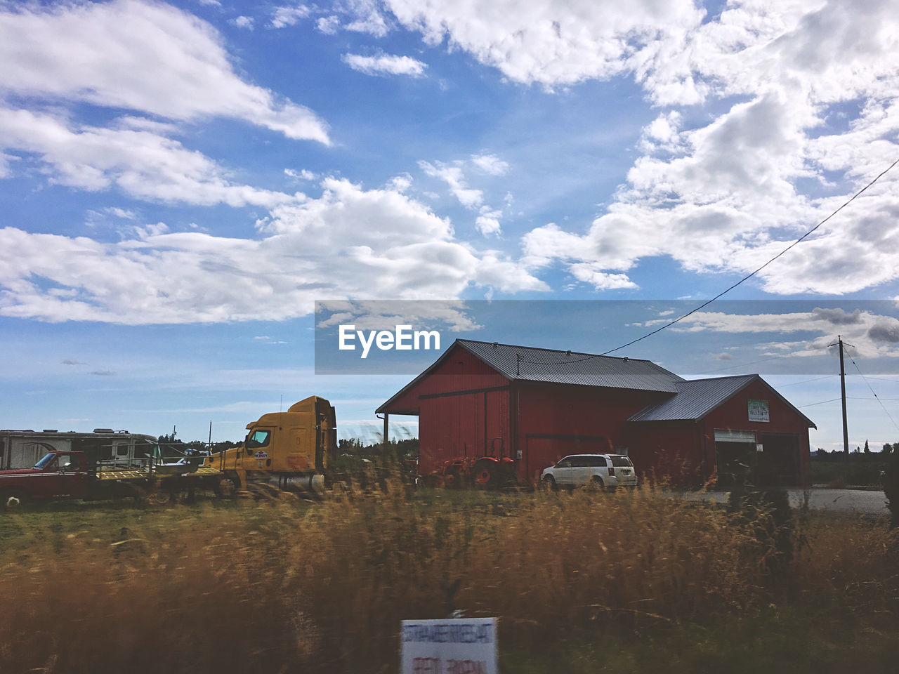 HOUSES BY FIELD AGAINST SKY