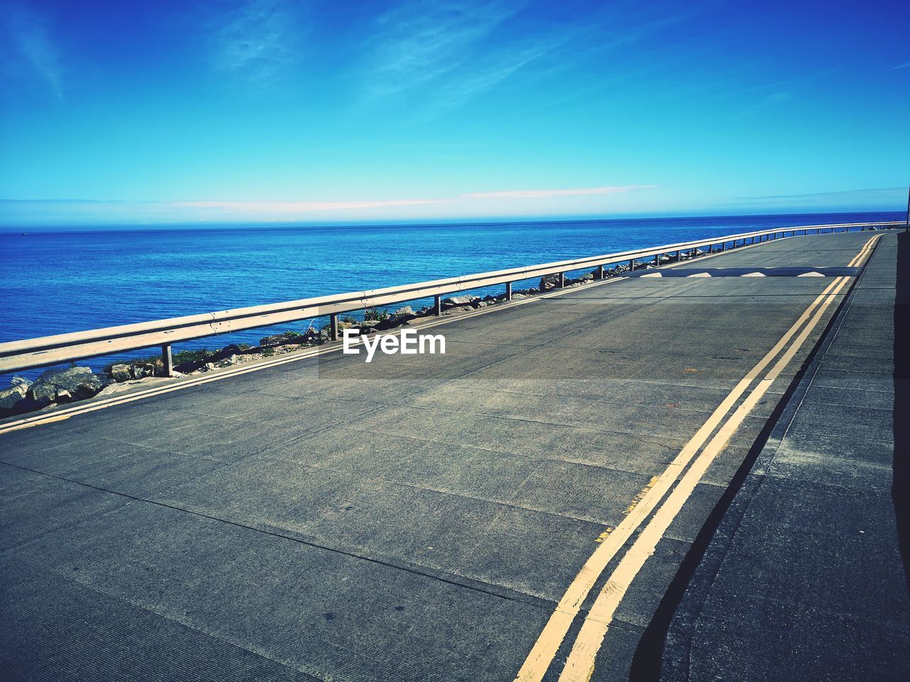 horizon, sky, transportation, sea, road, water, horizon over water, nature, coast, blue, ocean, road marking, no people, travel, marking, day, scenics - nature, symbol, mode of transportation, outdoors, the way forward, beauty in nature, city, dusk, sunlight, railing, street, clear sky, travel destinations, highway, asphalt, motion, architecture, land, beach, tranquil scene, reflection, tranquility, cloud, motor vehicle