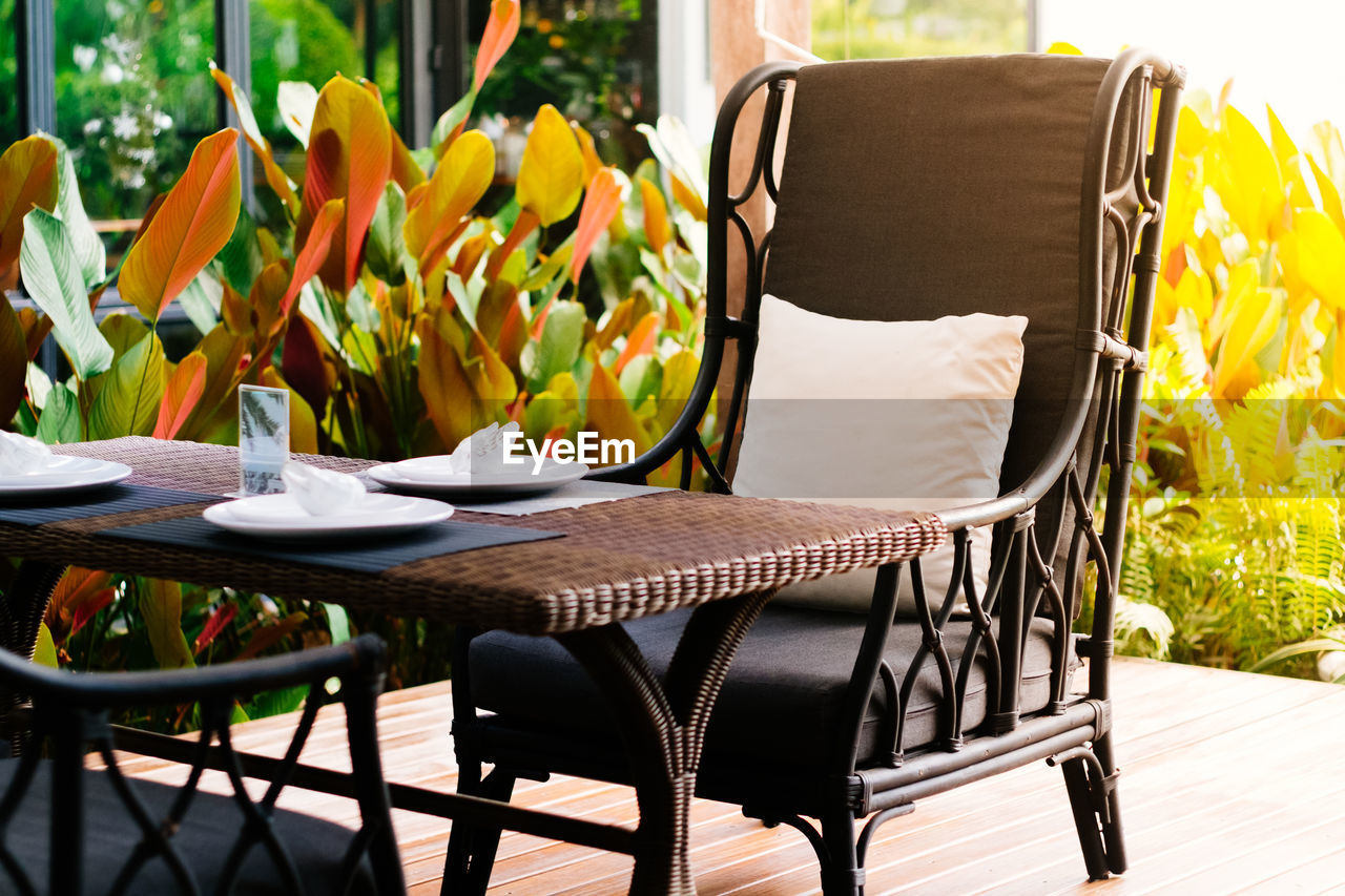 Close-up chair of the wooden dining table set with blur background of the garden