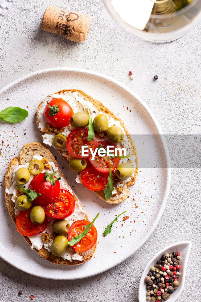 Bruschettas with olives and fresh tomatoes and wineglass
