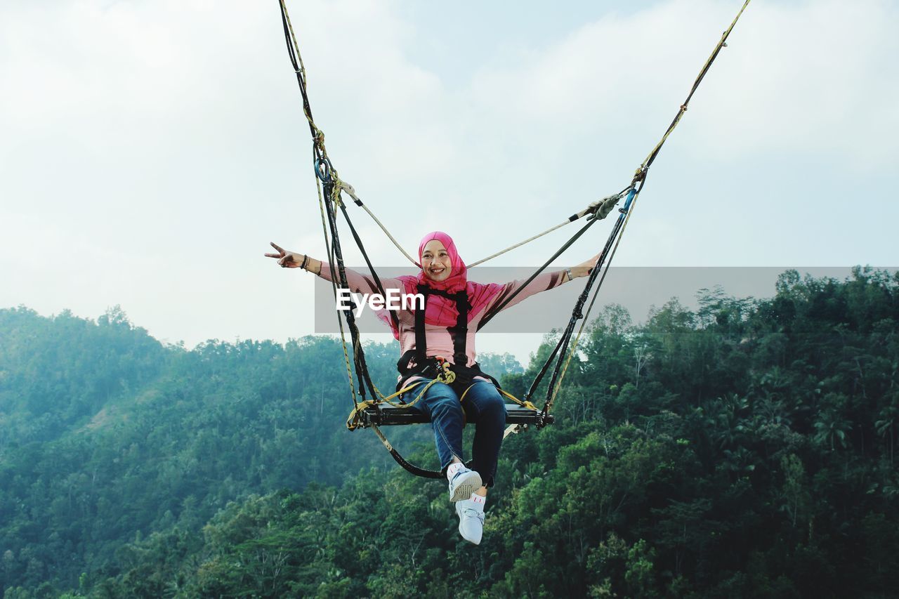 Person holding rope against trees in forest