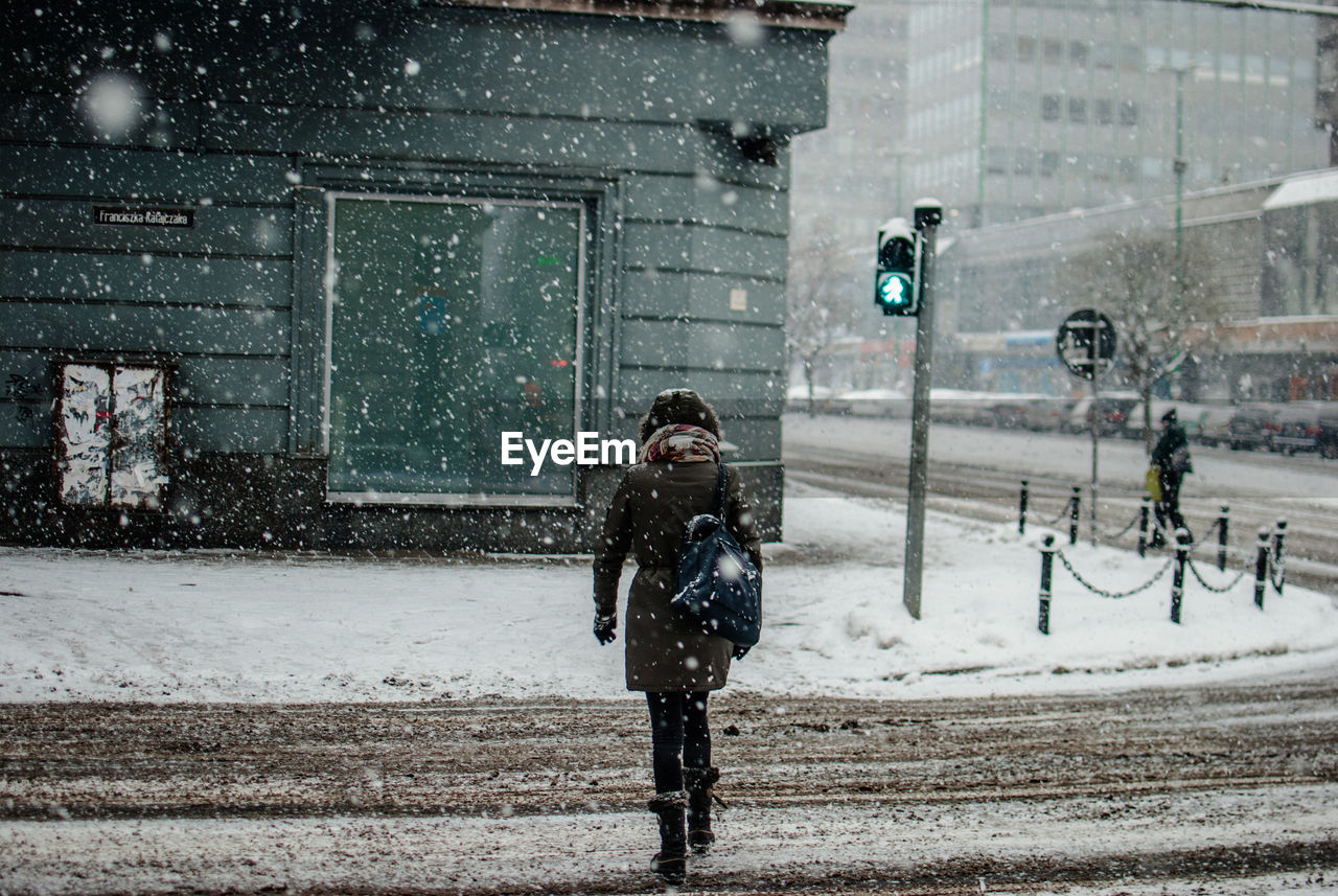 Rear view of woman crossing street during winter