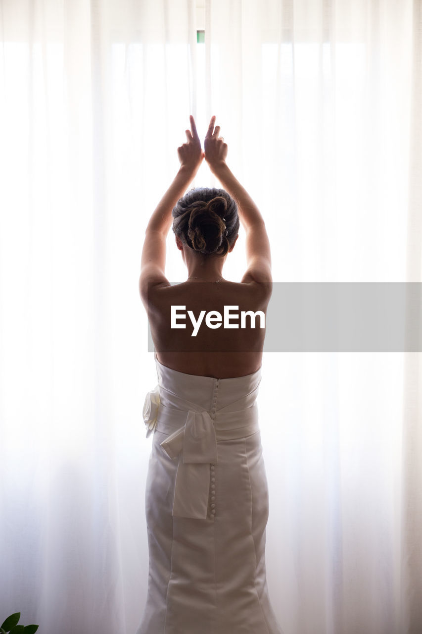 Rear view of bride opening curtain