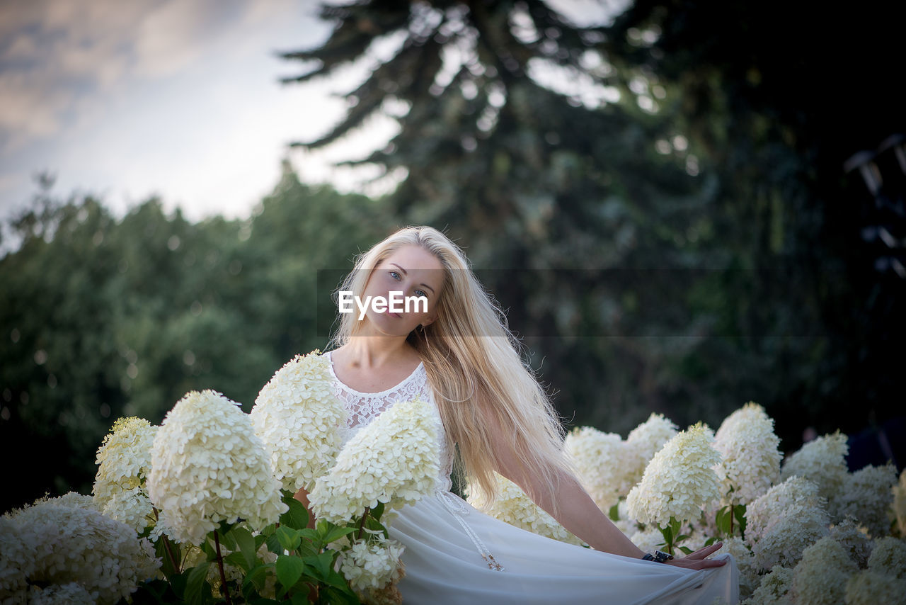 Portrait of smiling young woman against trees