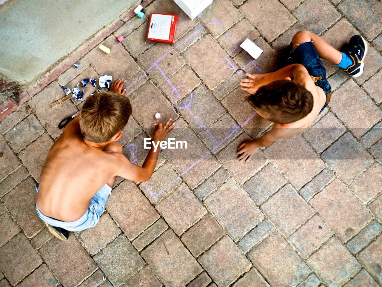 HIGH ANGLE VIEW OF MAN AND WOMAN SITTING ON STREET