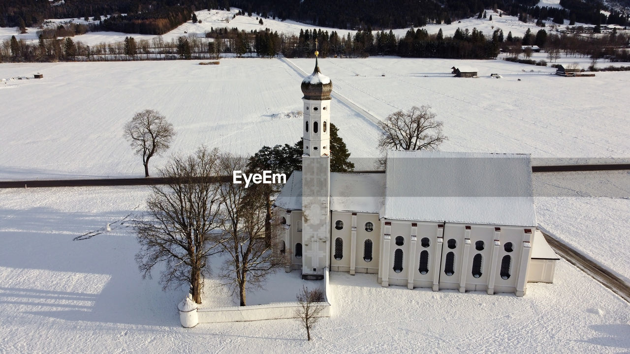 SNOW COVERED FIELD BY TREES AND BUILDINGS