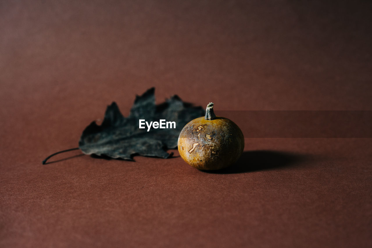 CLOSE-UP OF APPLE ON TABLE AGAINST ORANGE WALL