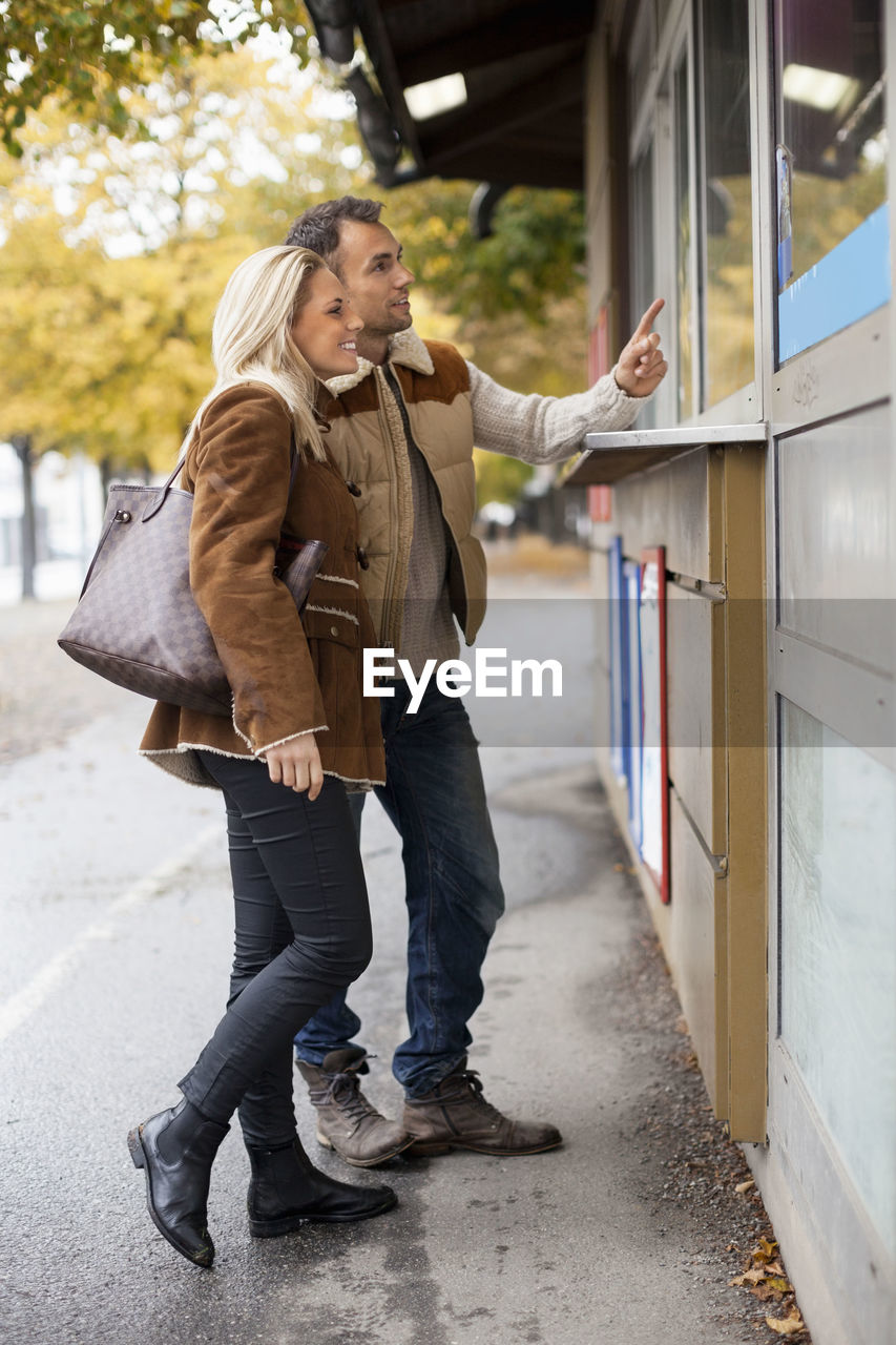 Young couple ordering food from store on street