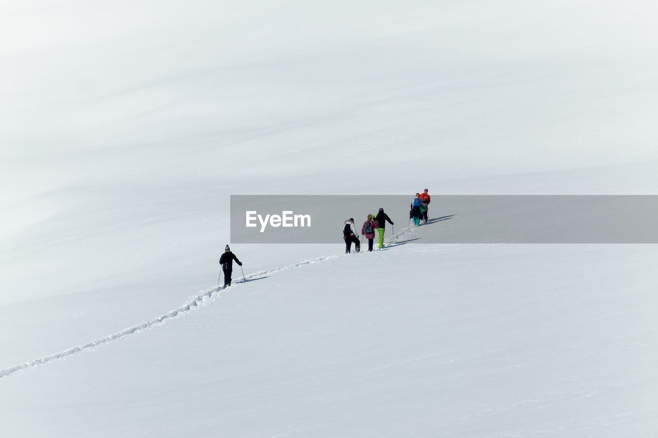 High angle view of people hiking on snow covered field