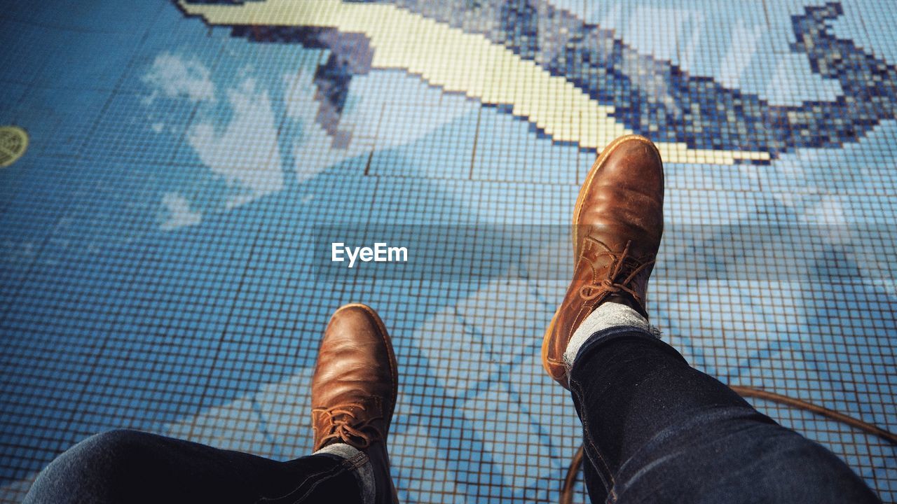 Low section of man sitting by swimming pool