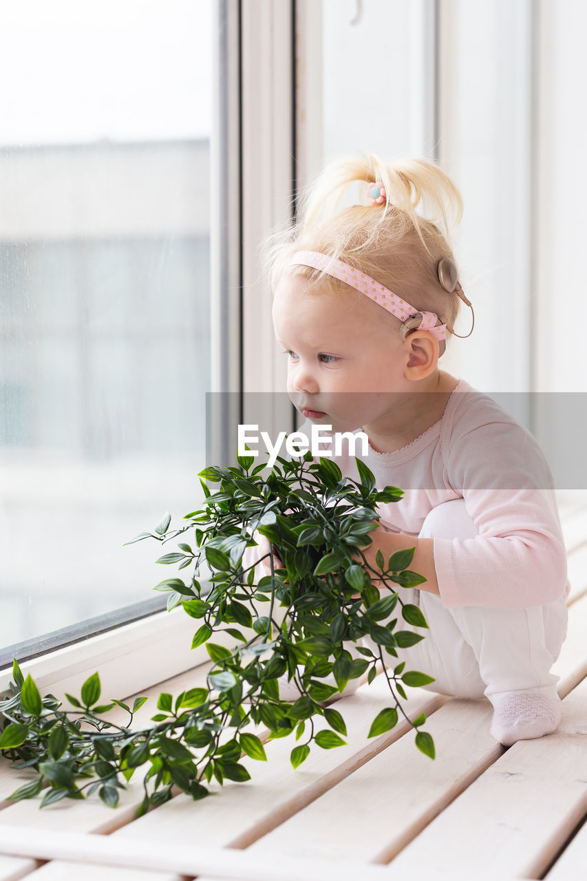 portrait of young woman standing by plant