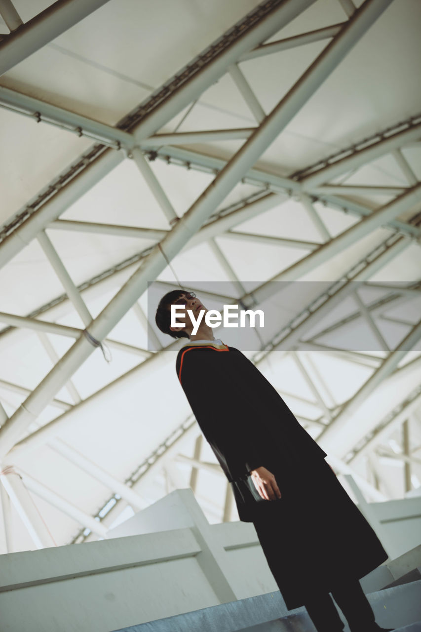 LOW ANGLE VIEW OF MAN STANDING ON RAILING