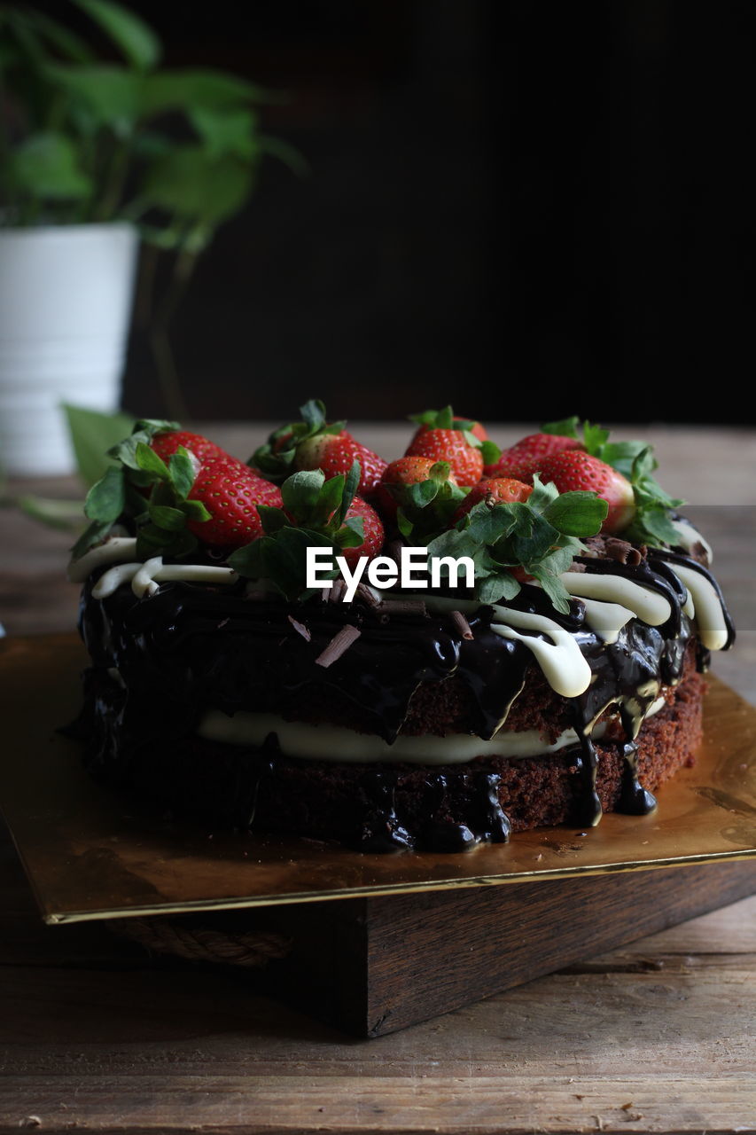 Moist chocolate cake with an overflow of cream cheese sauce and strawberry garnish