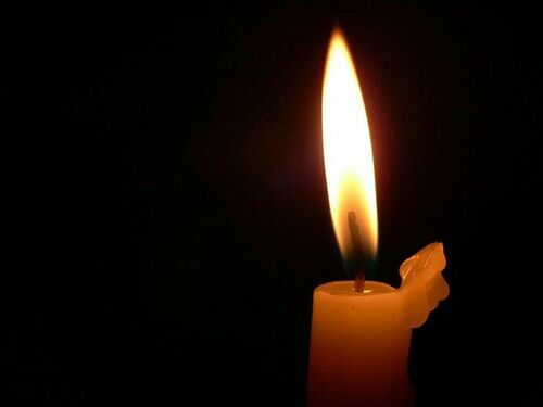 CLOSE-UP OF LIT CANDLE IN DARKROOM