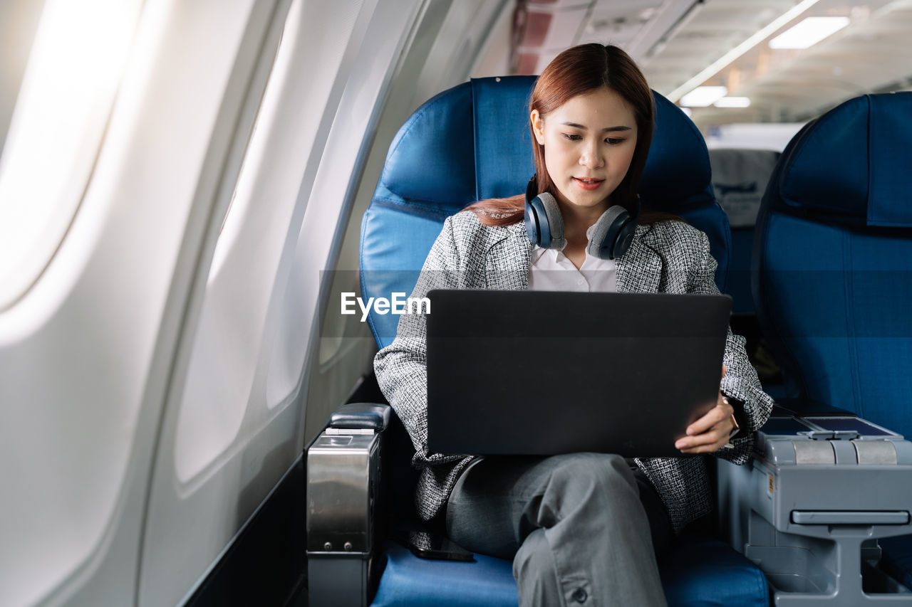 Businesswoman using laptop while sitting in airplane
