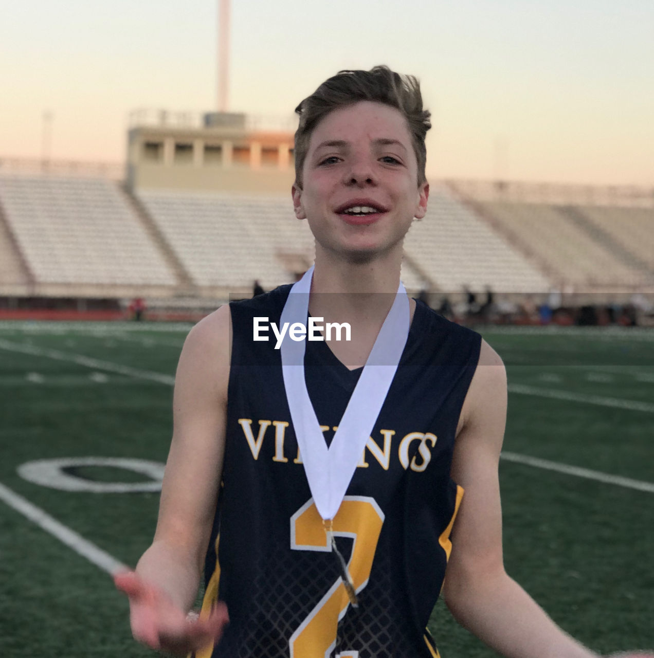 Portrait of young boy with winning medal on football field 