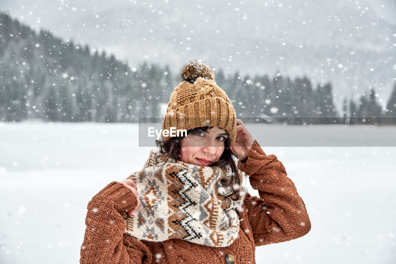 Portrait of woman wearing knit hat standing in snow