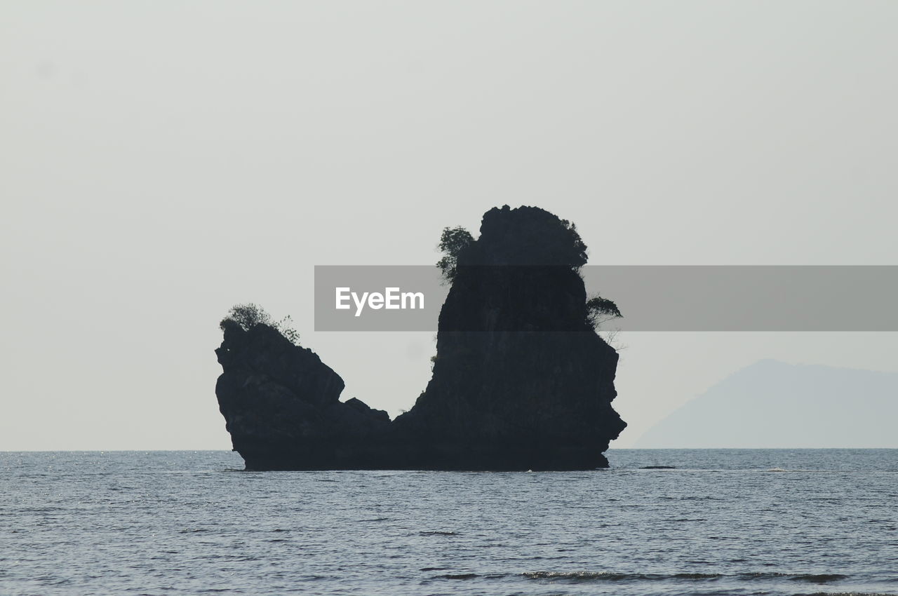 ROCK FORMATION BY SEA AGAINST CLEAR SKY