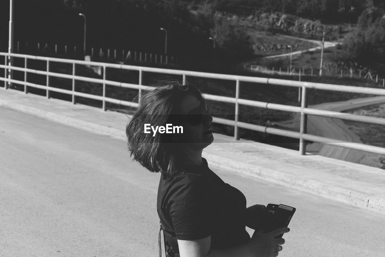 Side view of woman looking away while standing on road