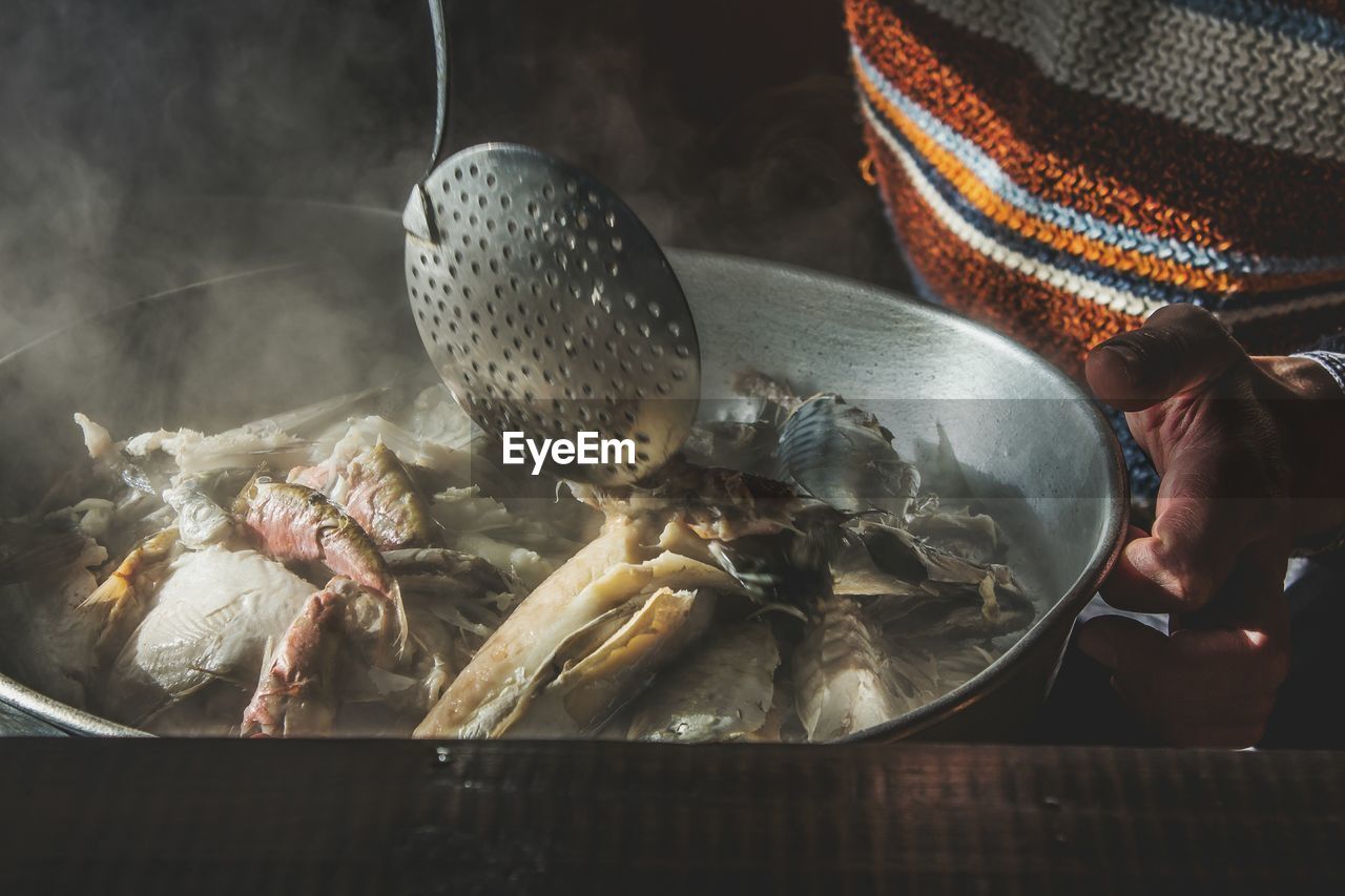 Full frame shot of man holding pan with cooked fish