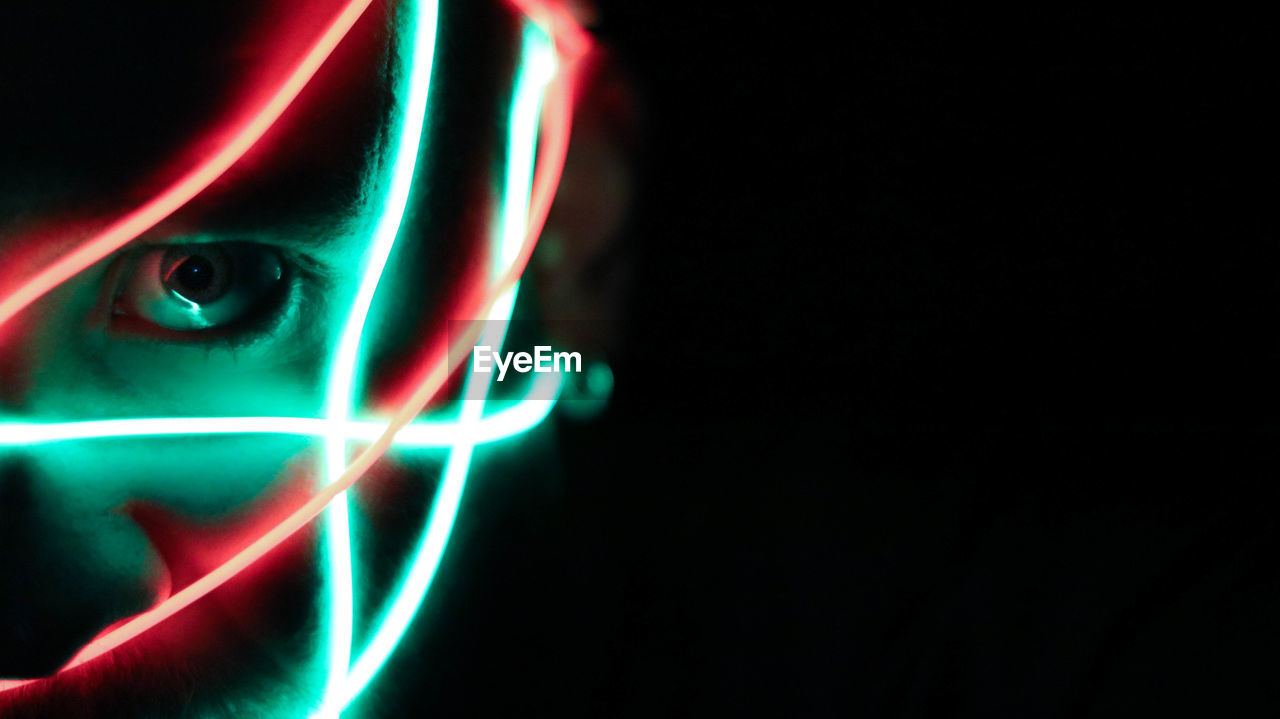 Cropped image of person with illuminated light in darkroom