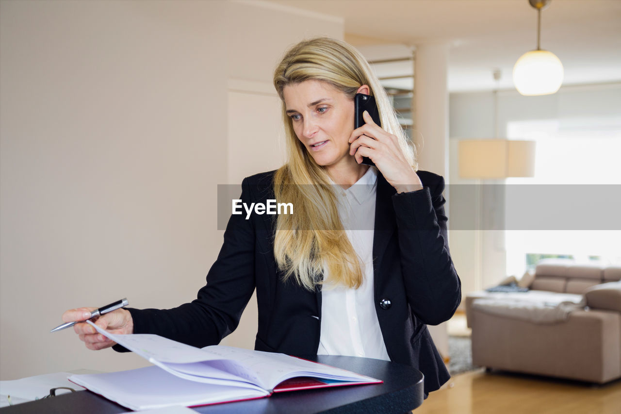 Businesswoman talking on smart phone while working in office
