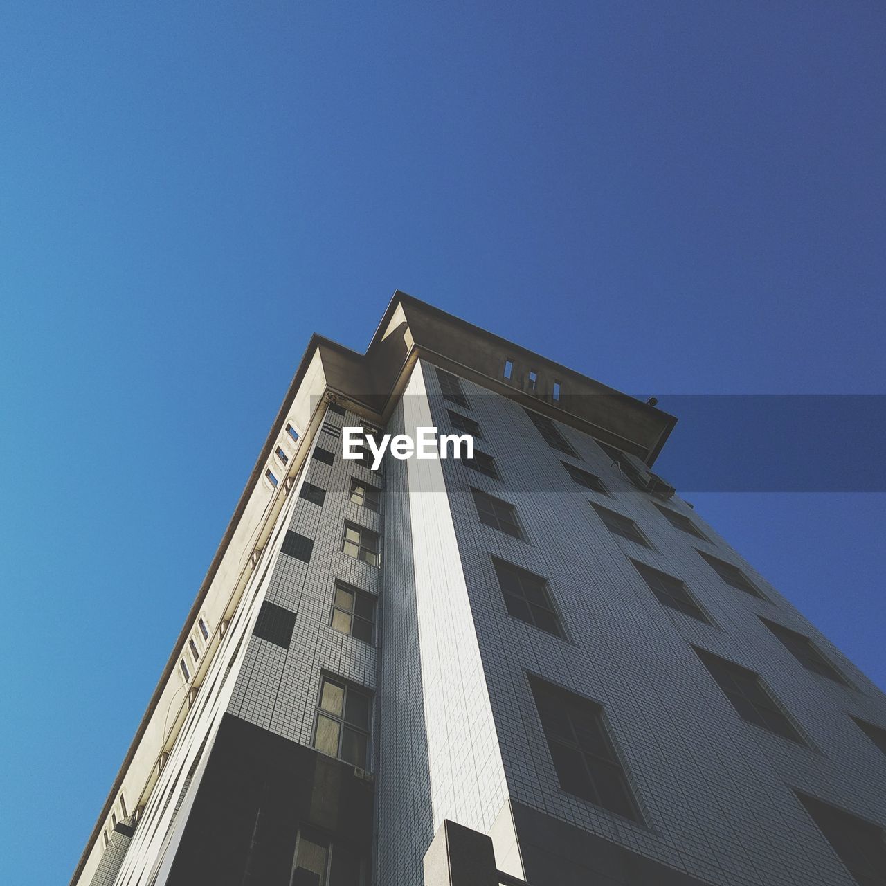 LOW ANGLE VIEW OF OFFICE BUILDING AGAINST CLEAR BLUE SKY