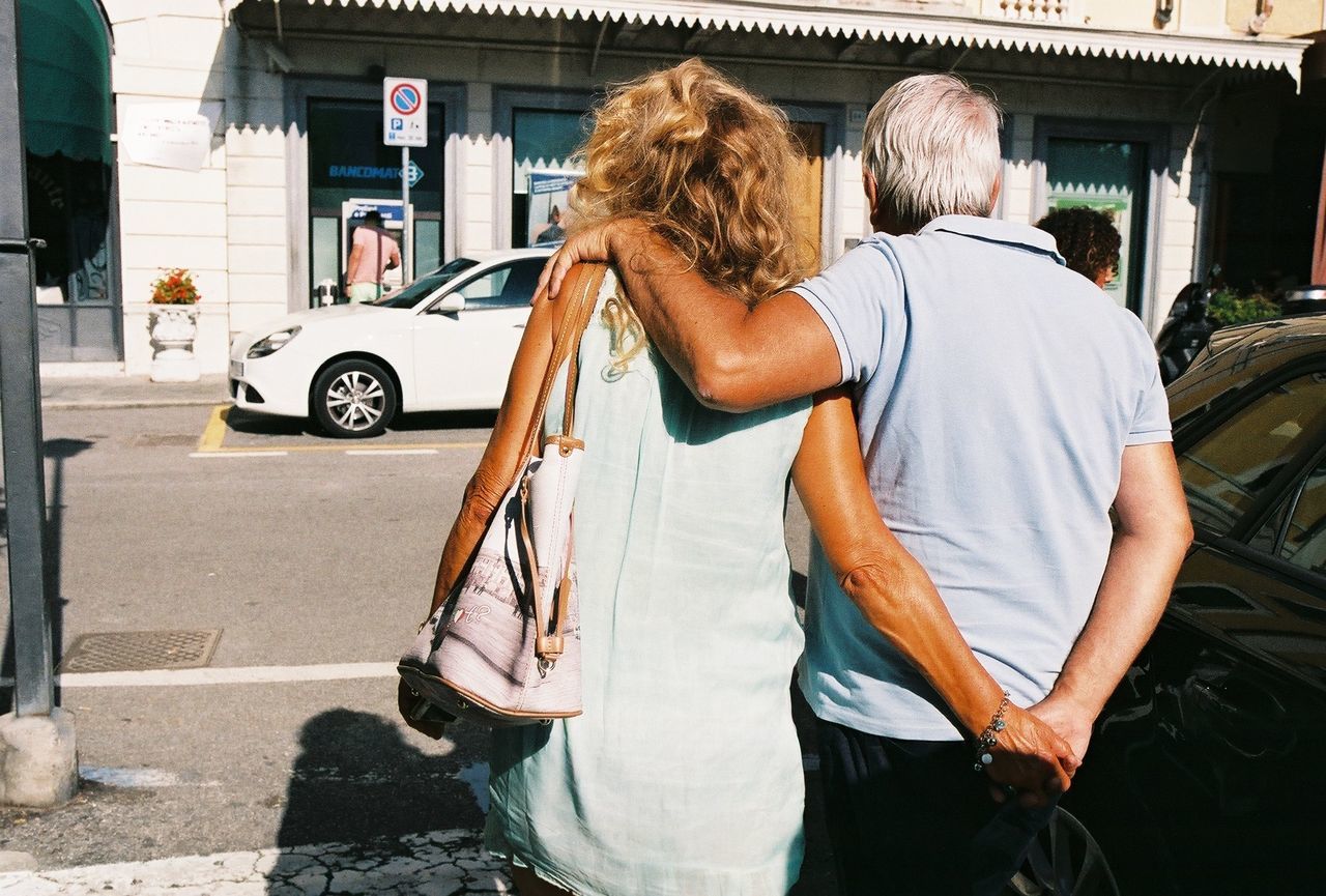 Rear view of senior couple walking on street in city
