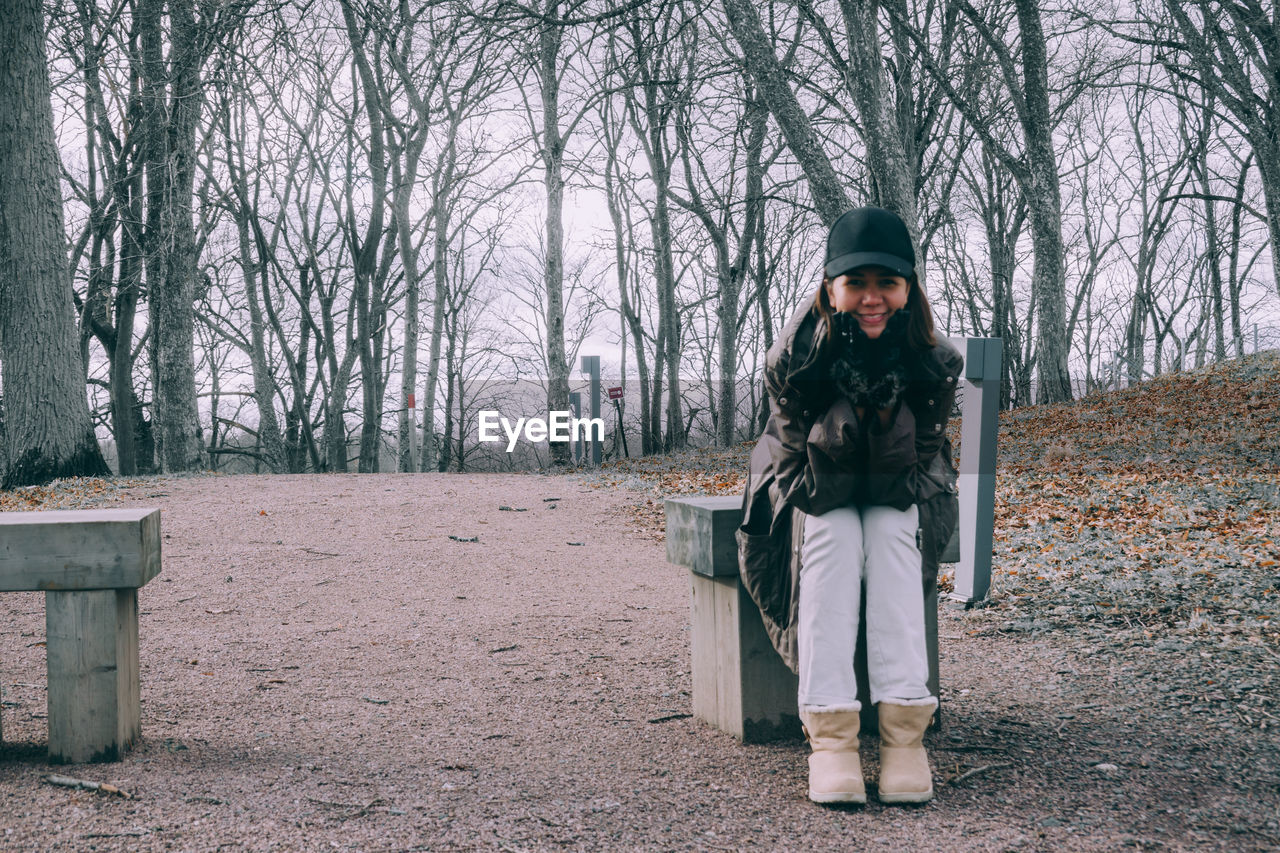 Portrait of woman sitting on snow covered bare trees