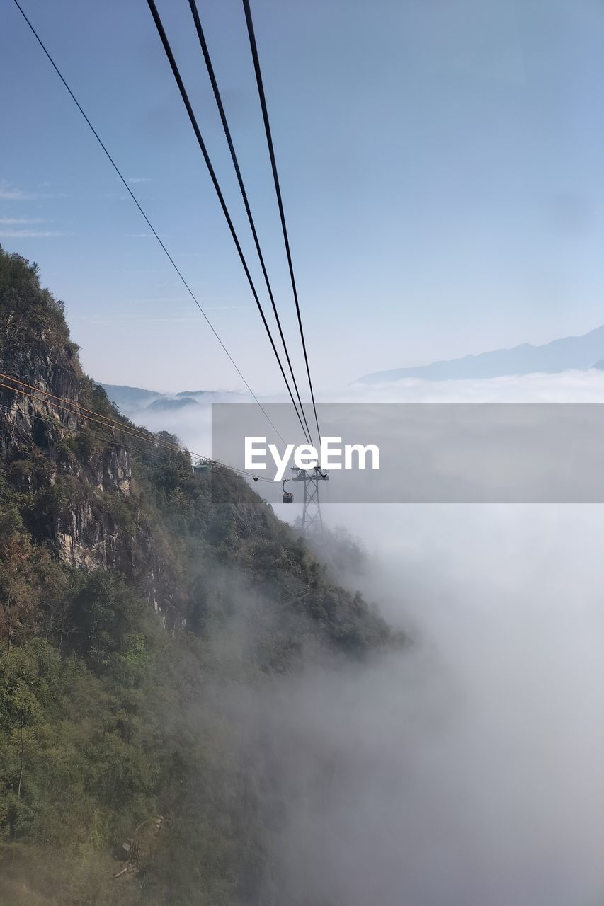 sky, cable, mountain, nature, cloud, environment, landscape, fog, scenics - nature, electricity, beauty in nature, no people, land, mountain range, travel, technology, outdoors, transportation, day, tranquility, tranquil scene, travel destinations, non-urban scene, power supply, power line, blue, cable car, water