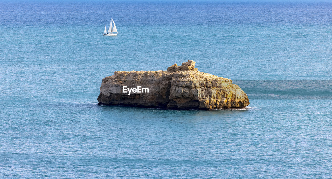 SCENIC VIEW OF ROCK FORMATION IN SEA AGAINST BLUE SKY