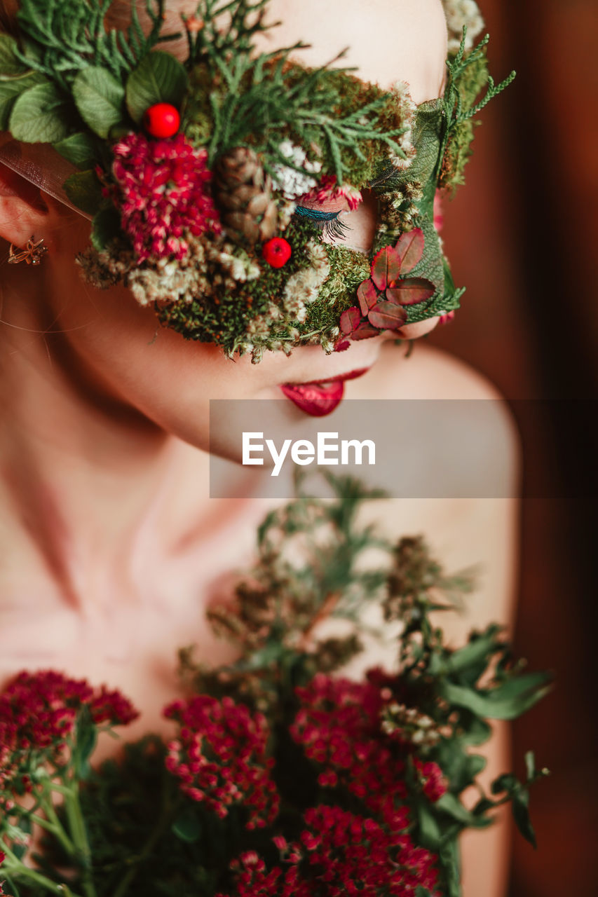 Close-up of woman with flower mask looking away