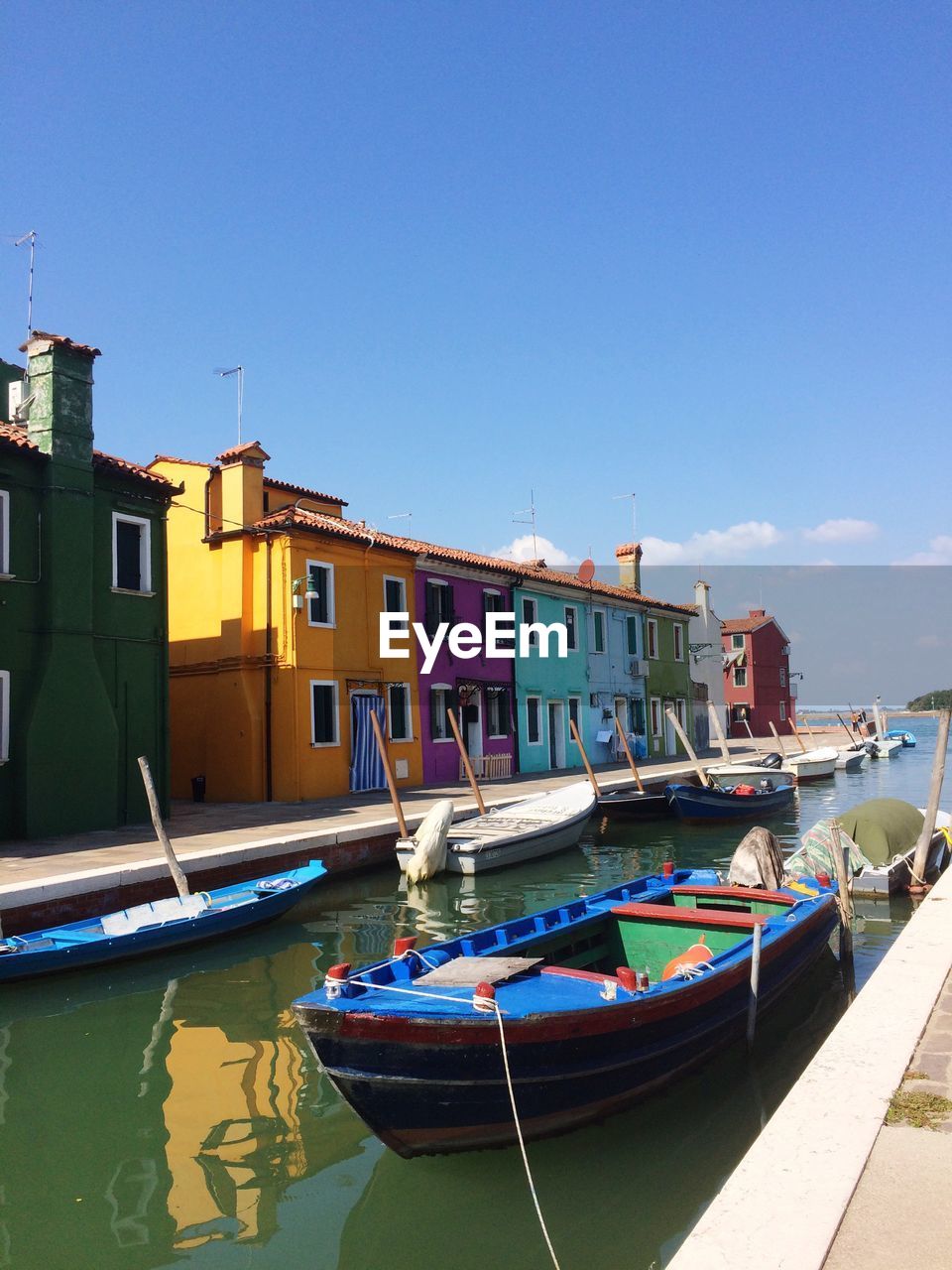 Boats moored on shore against clear blue sky