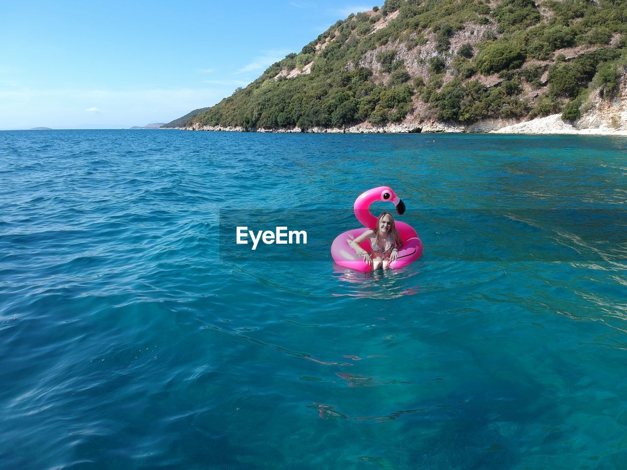 Woman swimming with pink inflatable ring in sea during sunny day