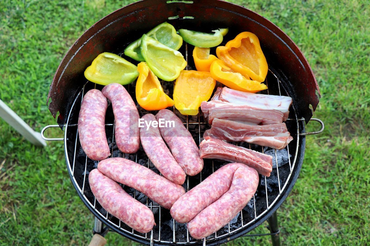 Directly above shot of sausages and vegetables being grilled on barbecue