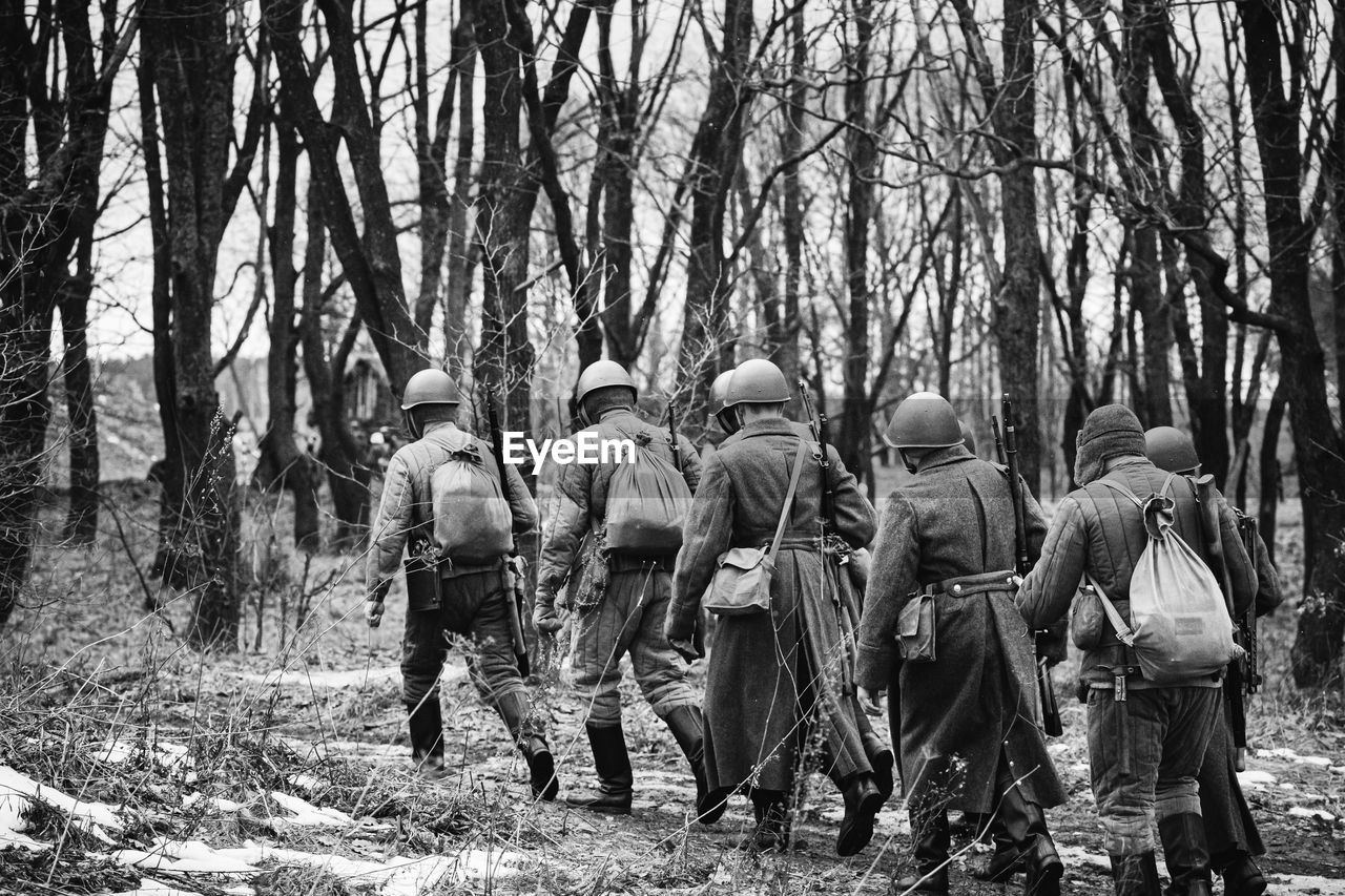 tree, group of people, land, plant, black and white, men, nature, forest, day, monochrome photography, adult, monochrome, crowd, person, troop, rear view, violence, lifestyles, outdoors, clothing, large group of people, full length, growth