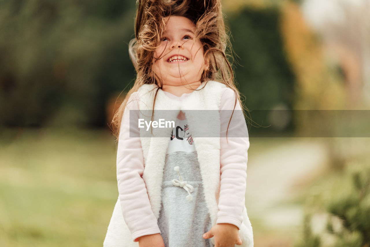 Girl looking away while standing outdoors