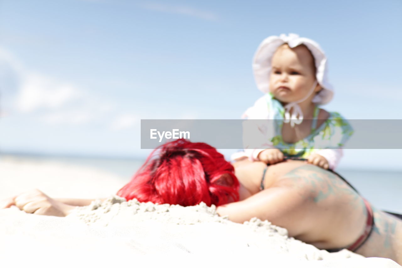 beach, child, baby, nature, land, women, childhood, sky, adult, water, clothing, emotion, sea, person, sand, female, photo shoot, sitting, two people, day, full length, relaxation, happiness, summer, holiday, smiling, lying down, toddler, blond hair, cute, vacation, outdoors, sunlight, trip, positive emotion, portrait, leisure activity, togetherness, focus on foreground, innocence, sunny, fashion, men, skin