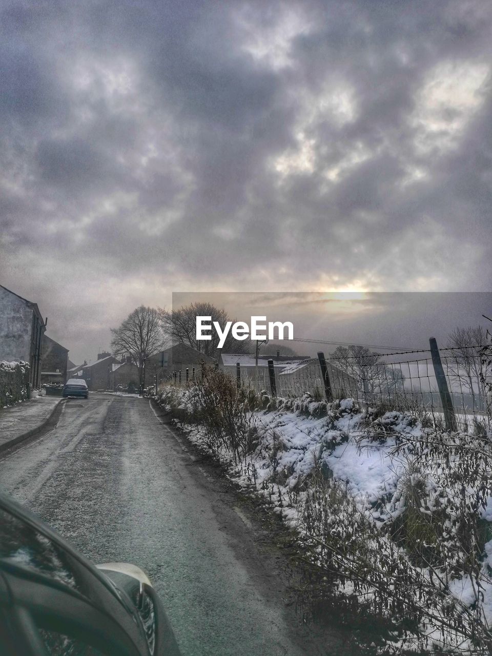 ROAD AMIDST BARE TREES AGAINST SKY