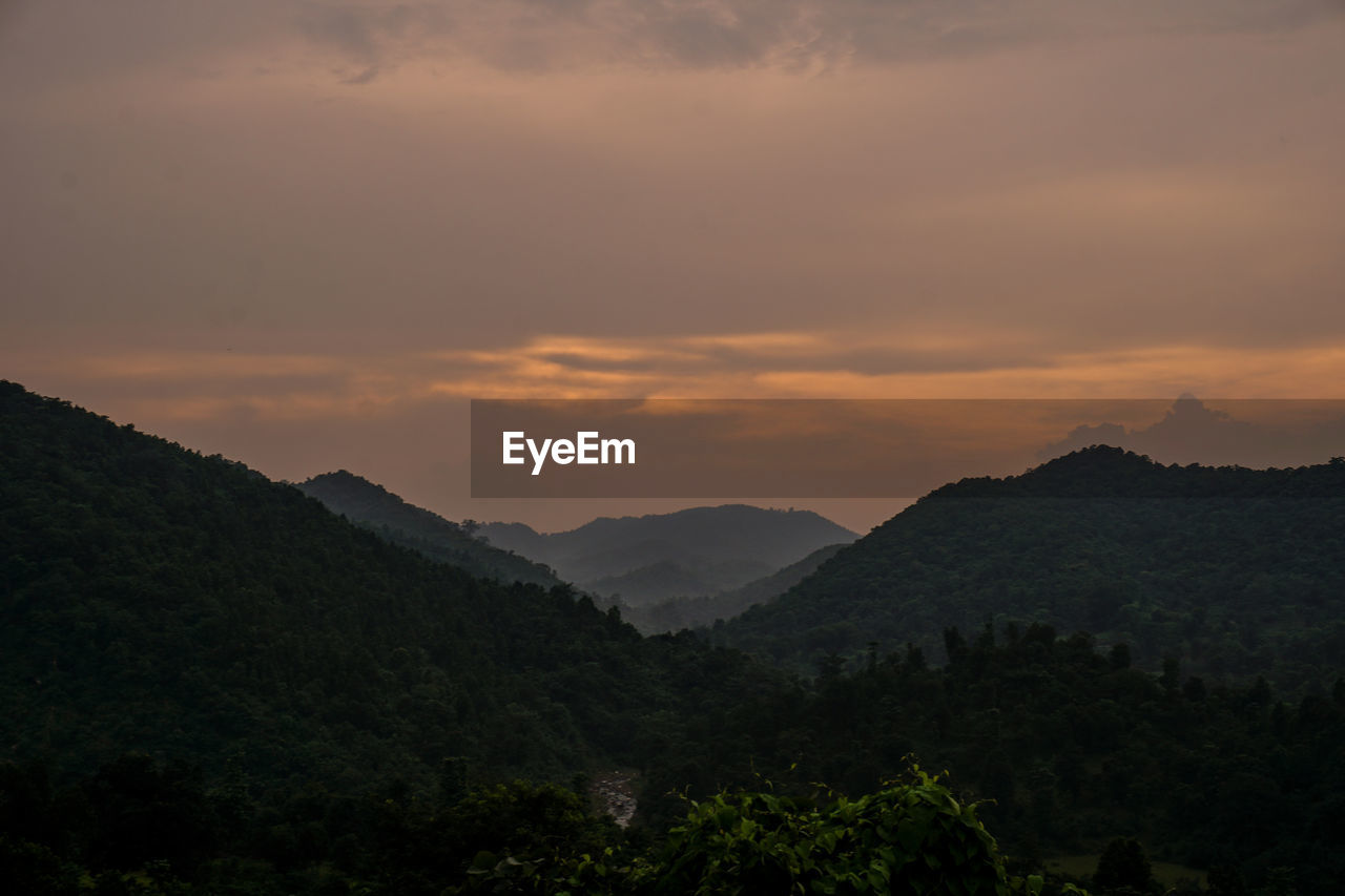 Scenic view of silhouette mountains against orange sky