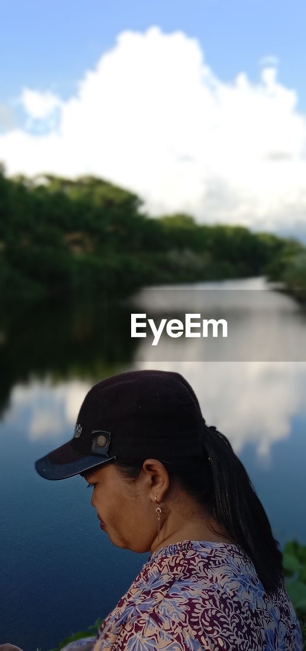 WOMAN LOOKING AT LAKE AGAINST SKY