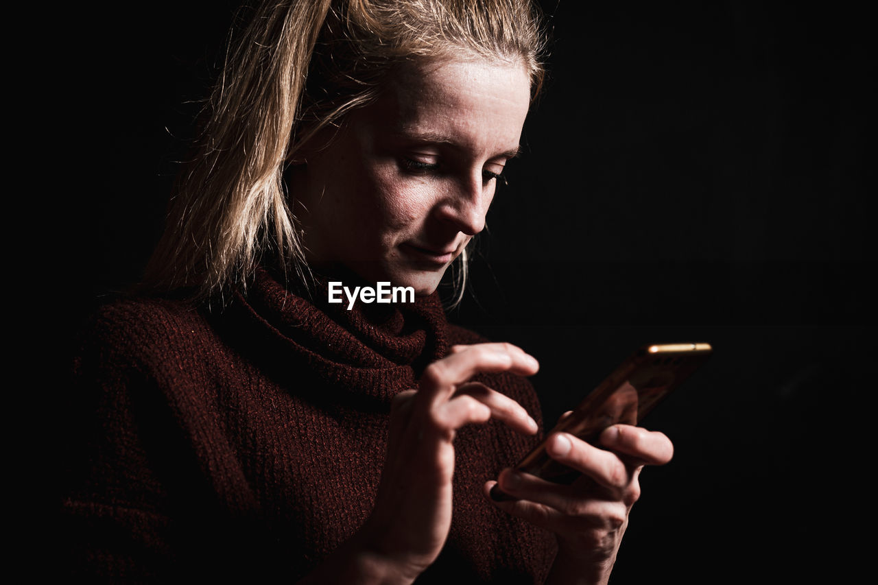 Close-up of woman using smartphone in darkroom