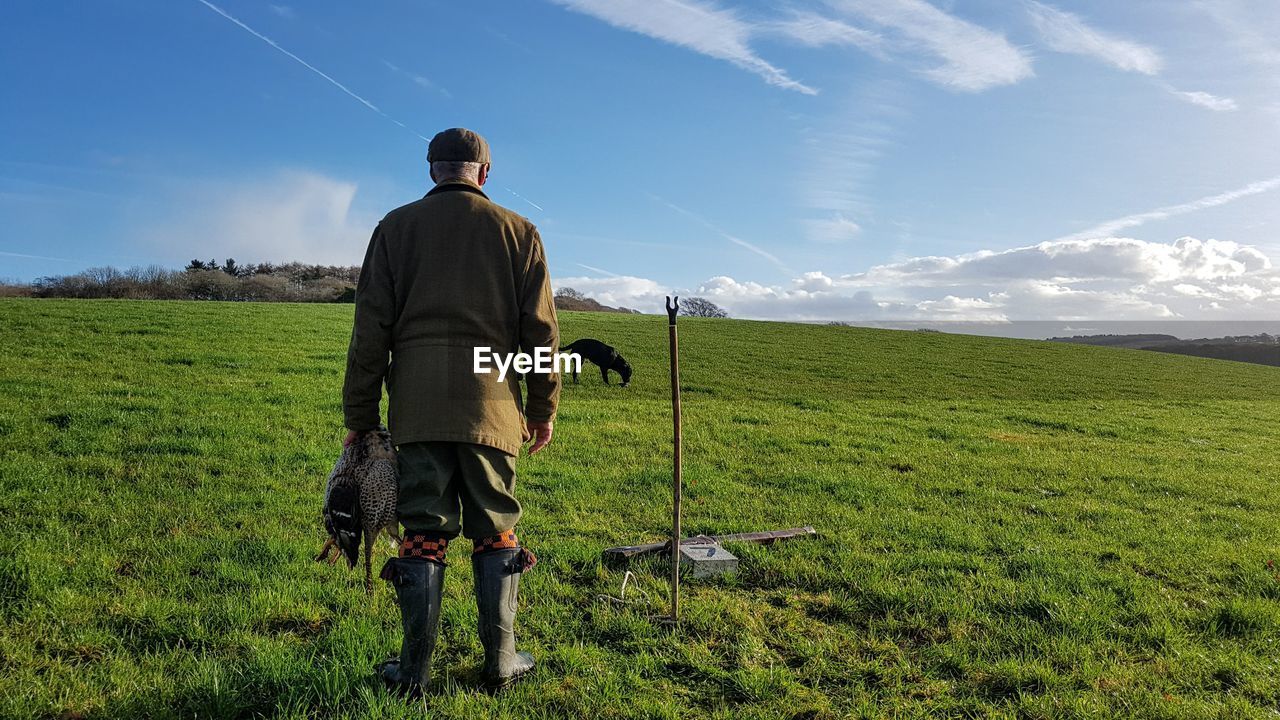 Full length rear view of man standing on field against sky