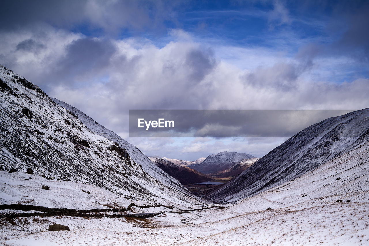 Scenic view of snow covered mountain against cloudy sky