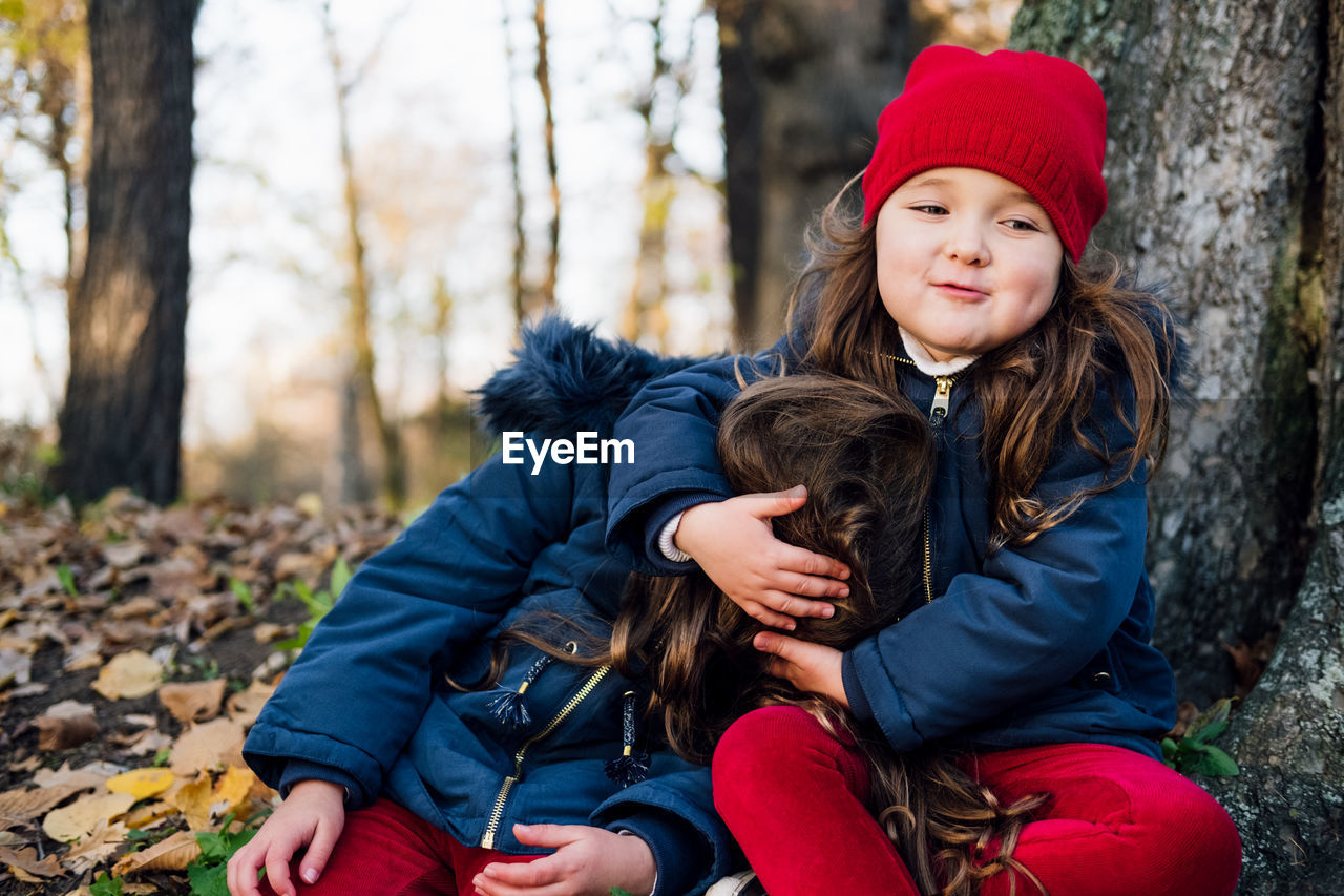 Smiling girl playing with sister in forest