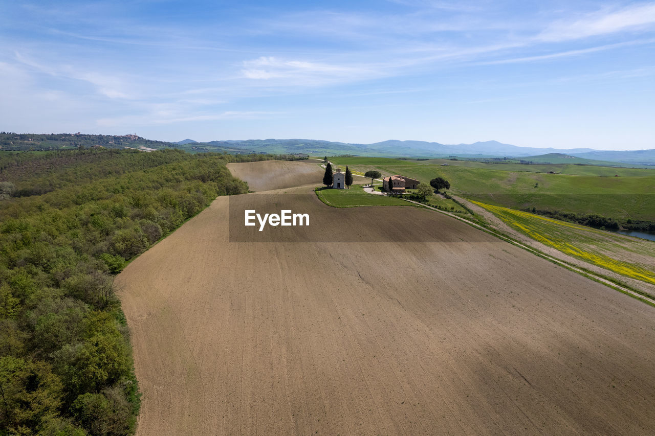 landscape, environment, transportation, road, sky, land, nature, hill, scenics - nature, travel, plant, highway, rural scene, beauty in nature, plain, rural area, non-urban scene, mode of transportation, field, natural environment, cloud, day, travel destinations, outdoors, agriculture, infrastructure, tree, tourism, grassland, blue, soil, motion, journey, grass, green, tranquility, horizon, activity, sunlight, adult, tranquil scene, asphalt, leisure activity, dirt, plateau, animal wildlife